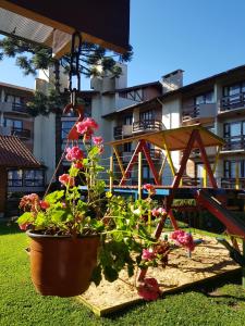 un jardín con una estructura de juegos y flores en un patio en Residencial Pousada do Serrano, en Gramado