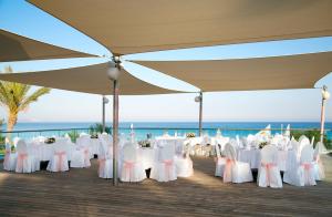 a row of tables and chairs under an umbrella on the beach at Asterias Beach Hotel in Ayia Napa