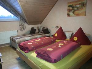 2 Betten in einem Zimmer mit roten und gelben Kissen in der Unterkunft Ferienwohnungen - Gästehaus Gertrud Moog- in Rust