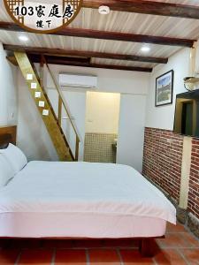 a bedroom with a white bed and a staircase at Kinmen Huquian 58 in Jinhu