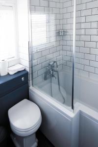 a white bathroom with a toilet and a bath tub at The Saracens Head in Stafford