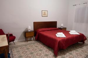 1 dormitorio con 1 cama roja y 2 toallas en Alloggio della Posta Vecchia, en Agrigento