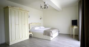 a white bedroom with a bed and a cabinet at Pensiunea Anastasia fosta Sofia in Remetea Mare