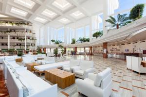 a lobby with white chairs and tables and windows at Landmar Playa La Arena in Puerto de Santiago