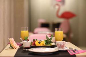 a table with a plate of fruit and two glasses of orange juice at Antidoto Rooms San Agustín - Recomendado para adultos in Toledo
