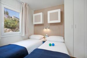 two beds in a small room with a window at Marina Camping Resort by Valamar in Rabac