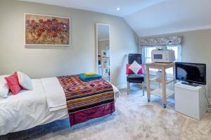 a bedroom with a bed and a television and a desk at Lingwood Hall in Lingwood