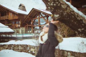 a woman walking in the snow in front of a house at Le Hameau Albert 1er in Chamonix