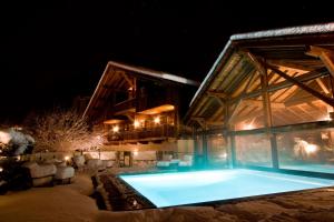 une maison avec une piscine la nuit dans l'établissement Le Hameau Albert 1er, à Chamonix-Mont-Blanc
