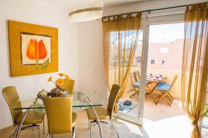 a dining room with a glass table and yellow chairs at Apartment Delfines Sand Corralejo By Holidays Home in Corralejo