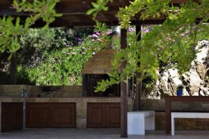 a stone fireplace in a garden with pink flowers at Marvelous Sea View Eco Apt in Ammouliani