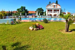 a yard with a house and a swimming pool with flowers at Elea Hotel Apartments and Villas in Argassi