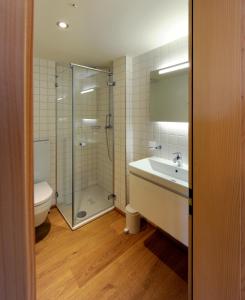 ein Badezimmer mit einer Dusche, einer Badewanne und einem Waschbecken in der Unterkunft Hotel Sternen in Lenk im Simmental