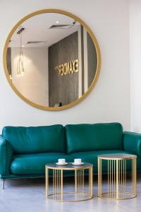 a green couch and gold tables in a room with a mirror at Hotel Alexander in Krakow