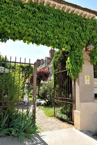 an entrance to a garden with an iron gate at LOGIS - Hôtel Restaurant Les Tilleuls in Saint-Florentin