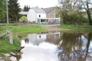 un granero reflejado en un estanque frente a una casa en Le gîte de l Ourthe, en Ortheuville
