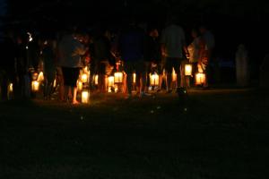 un grupo de personas sosteniendo velas encendidas en la oscuridad en Grand Oak Manor Bed and Breakfast, en Granville Ferry