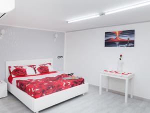 a bedroom with a bed with red sheets and a table at Short Lets Lulù in Ercolano