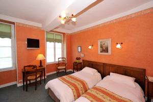 a bedroom with two beds and a desk and a tv at LOGIS - Hôtel Restaurant Les Tilleuls in Saint-Florentin