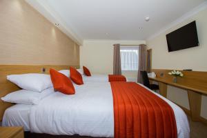 a hotel room with a large bed with red pillows at Hill Park Hotel in Rosyth