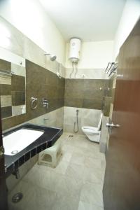 a bathroom with a tub and a toilet and a sink at Hotel Vaishnavi in Jaipur