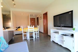 a living room with a flat screen tv and a dining room at Marina Beach Hollidays Mimosa in Empuriabrava
