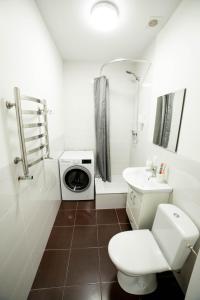 a bathroom with a toilet and a sink and a washing machine at Vicheva apartments in Lviv