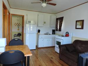 Il dispose d'une cuisine et d'un salon avec un canapé et une table. dans l'établissement Centennial Cottages, à Brackley Beach