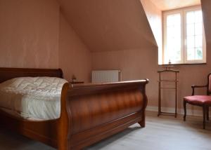 1 dormitorio con 1 cama, 1 silla y 1 ventana en La ferme des Cailloux, en Sassay