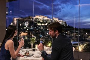 
a man and woman sitting at a table with wine glasses at Electra Metropolis in Athens
