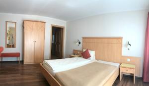 a bedroom with a large bed and a red chair at Hotel Kreuz in Holderbank