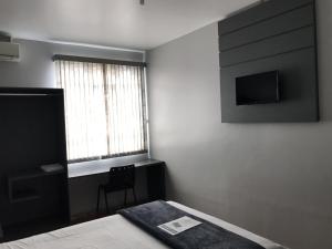 a bedroom with a bed and a television on the wall at Euro Hotel in Ubiratã