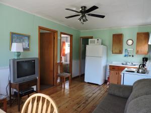 Il dispose d'une cuisine et d'un salon avec un canapé et un réfrigérateur. dans l'établissement Centennial Cottages, à Brackley Beach