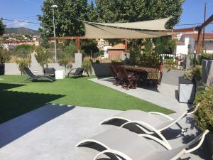 eine Terrasse mit Stühlen, einem Tisch und Gras in der Unterkunft Villa Masnou Homelydays in El Carrer del Canonge