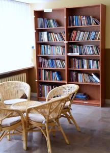 two chairs and a table in a room with bookshelves at Dobre Miejsce Dom Rekolekcyjny in Warsaw