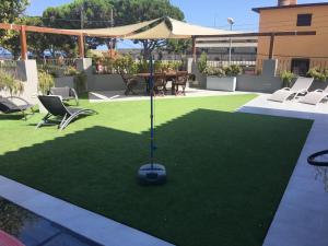 einen künstlichen Rasenplatz mit einem Tisch und Stühlen in der Unterkunft Villa Masnou Homelydays in El Carrer del Canonge