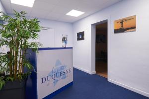un couloir de bureau avec des plantes et un panneau indiquant ralentir le divorce dans l'établissement Hotel Le Petit Duquesne, à Nantes