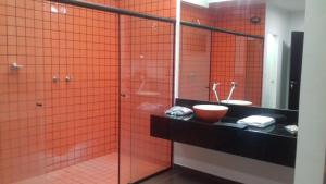 baño de azulejos de color naranja con lavabo y espejo en Elegance Motel, en São Paulo