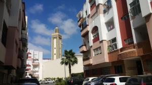 un bâtiment avec une tour d'horloge au milieu d'une rue dans l'établissement Sunny appart Residence Nour Californie, à Casablanca