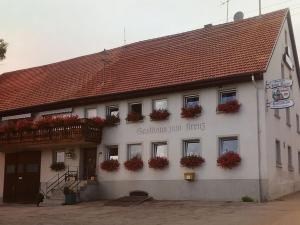 Gasthaus zum Kreuz في غرافنهاوسن: مبنى أبيض وبه زهور حمراء على النوافذ