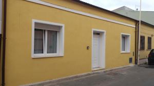 a yellow building with two windows and a door at Da Valentina B&B in Elmas