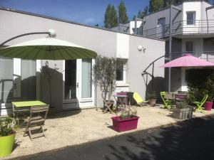 a patio with tables and chairs and an umbrella at B Hotel Caen Mondeville in Mondeville