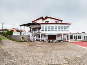 a large white house with tables and chairs in front of it at Chalet Areo do rio - playa de razo in Razo