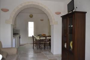 eine Küche und ein Esszimmer mit einem Torbogen und einem Tisch in der Unterkunft Trullo Amico in Cisternino