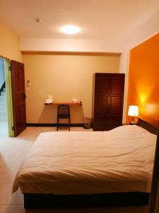 1 dormitorio con 1 cama y 1 mesa con silla en Kinmen Backpacker en Jincheng