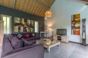 a living room with a couch and a tv at VILLA Nuri Merah 1 in Kerobokan