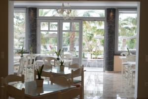 a restaurant with white tables and chairs and large windows at Castro Hotel in Kamari