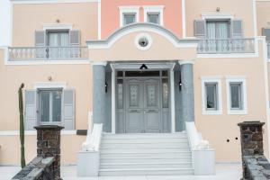 a pink house with a grey door and stairs at Castro Hotel in Kamari