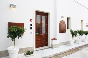 a front door of a white building with potted trees at La Nicchia Smart in San Vito lo Capo