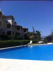 a large blue swimming pool in front of a house at Apartamento Las Brisas in Mijas
